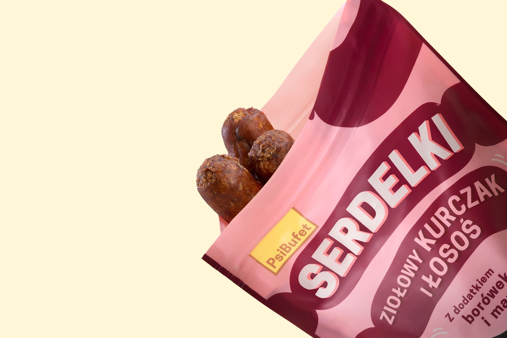 A pink package of "Serdelki" dog treats with herbal chicken and salmon flavor, partially open to reveal the treats on a plain background.